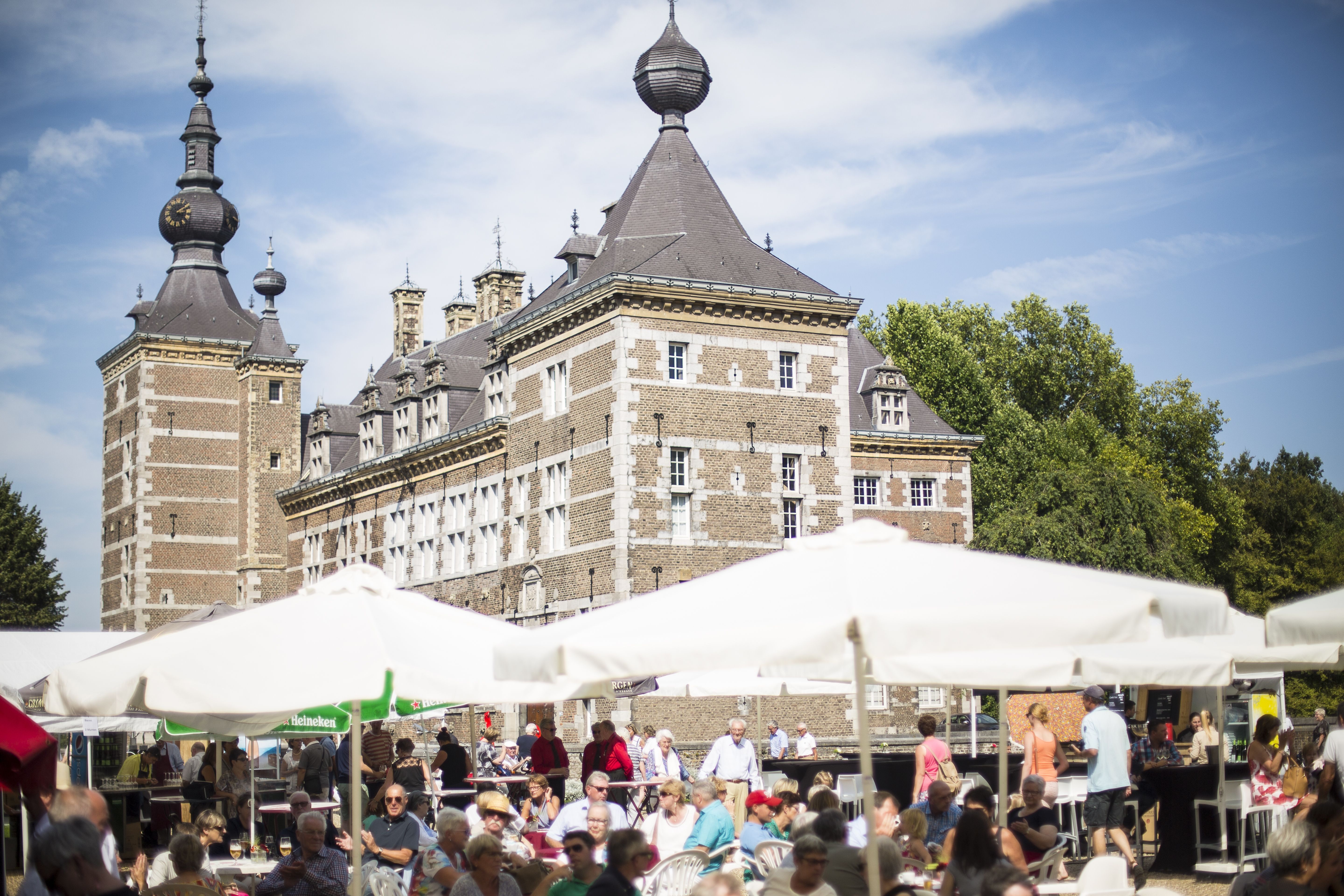 Kasteel met witte parasols en bezoekers in de tuin van het kasteel